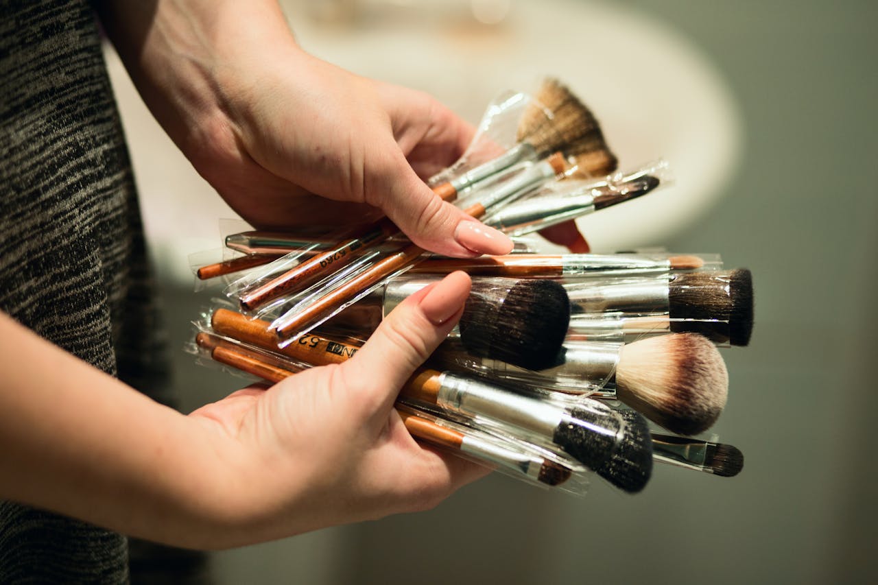 A variety of makeup brushes held in hands, ideal for beauty and cosmetic themes.